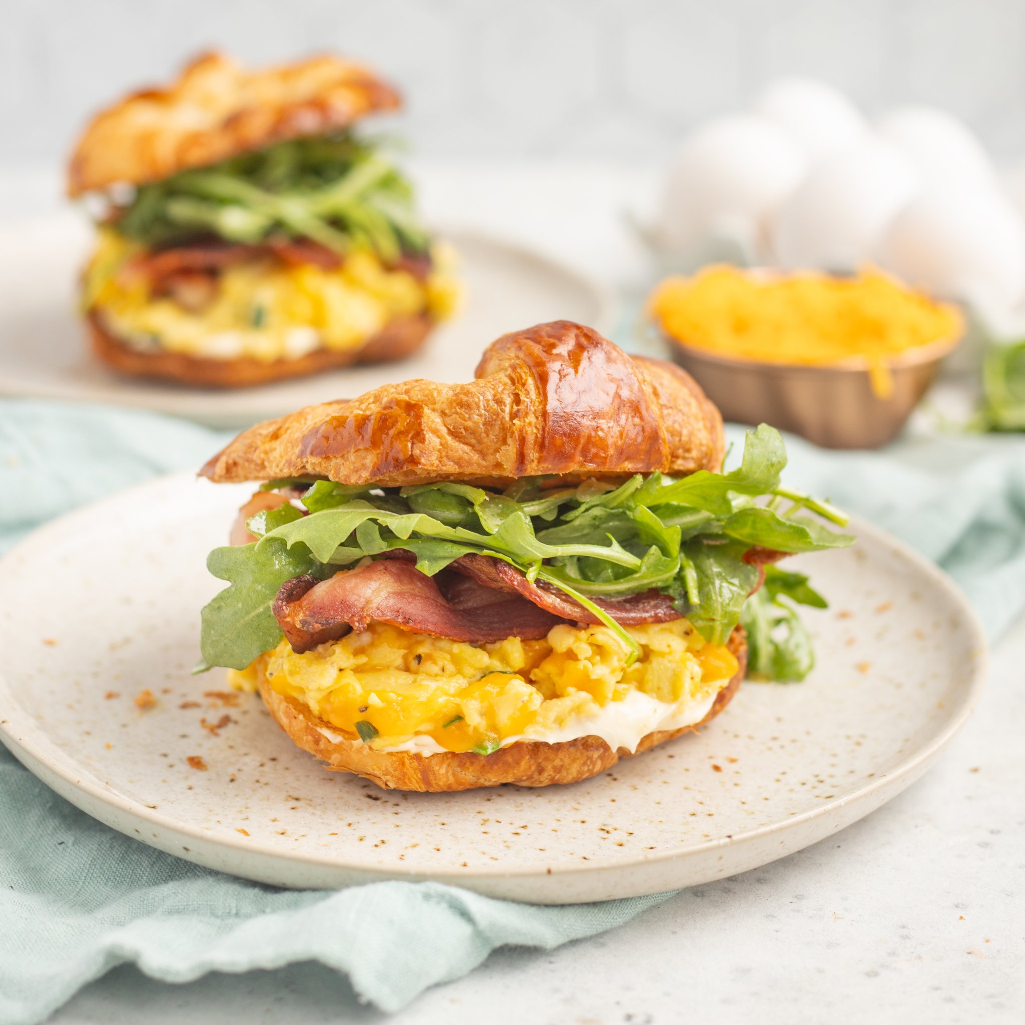 Toasted Croissant Breakfast Sandwiches with Cheesy Eggs, Bacon, Chives